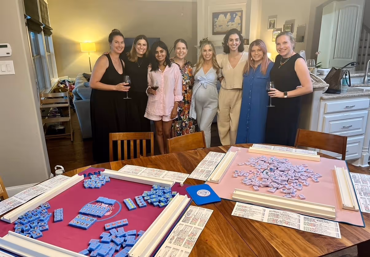 A group of friends gathered together at a Mahjong Standard evening, dressed up and smiling